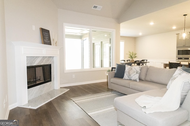 living room featuring recessed lighting, a high end fireplace, visible vents, vaulted ceiling, and dark wood finished floors