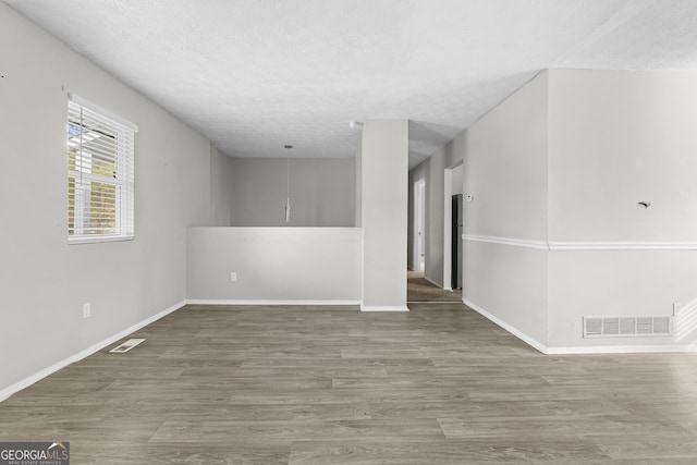 unfurnished room with a textured ceiling and hardwood / wood-style flooring