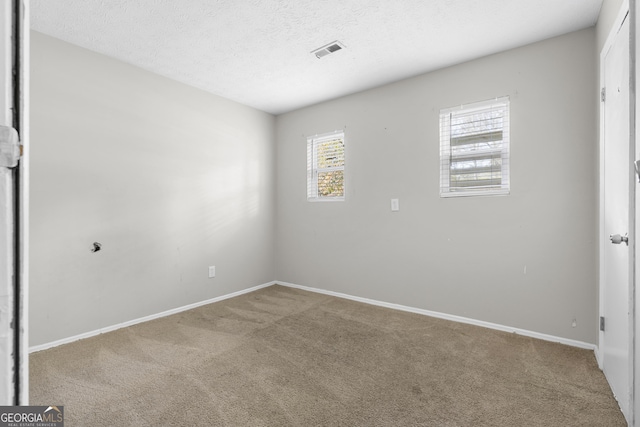 carpeted empty room with a textured ceiling