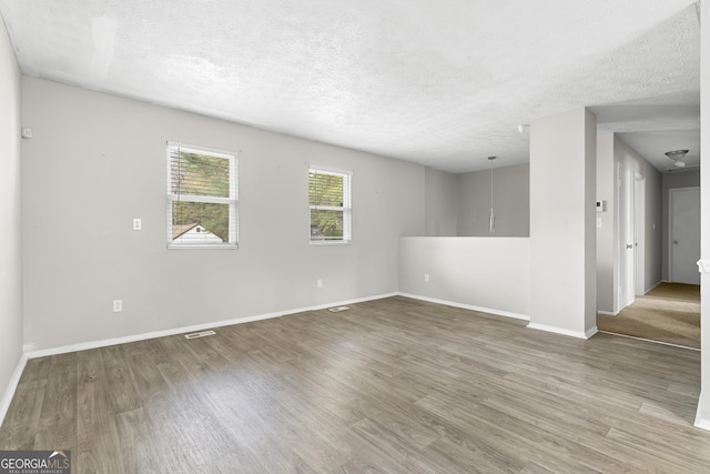 unfurnished room with a textured ceiling and hardwood / wood-style flooring