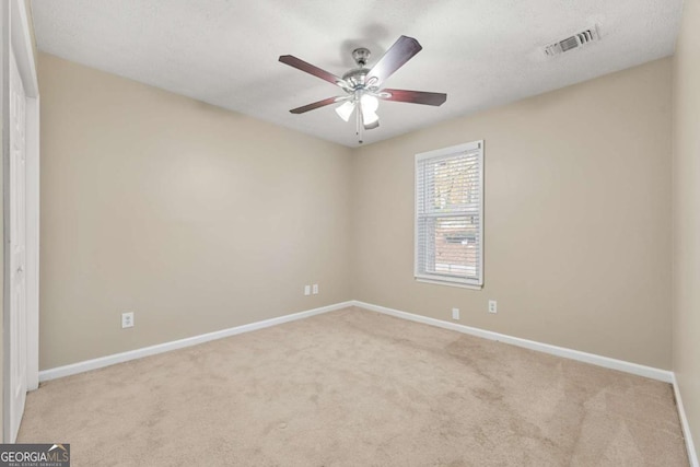 spare room featuring ceiling fan, light colored carpet, and a textured ceiling