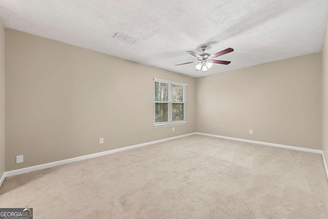 carpeted empty room featuring ceiling fan and a textured ceiling