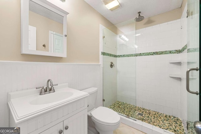 bathroom featuring a shower with door, vanity, a textured ceiling, and toilet