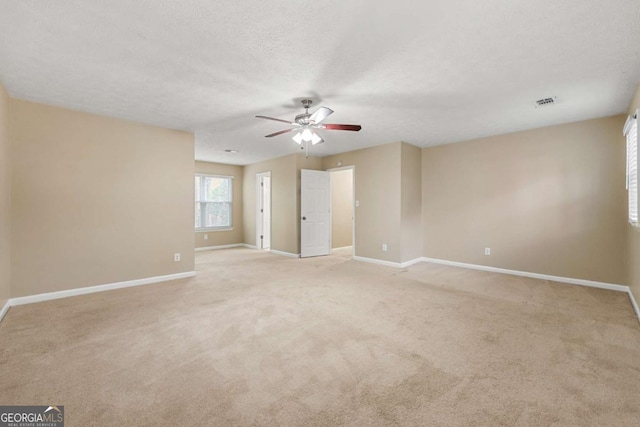 unfurnished room featuring ceiling fan, light colored carpet, and a textured ceiling