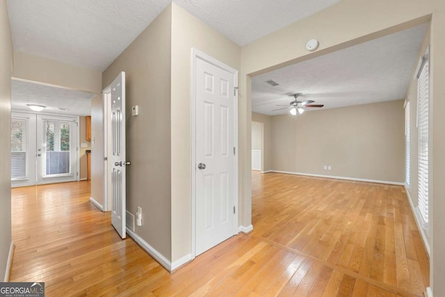 hall featuring french doors, wood-type flooring, and a textured ceiling