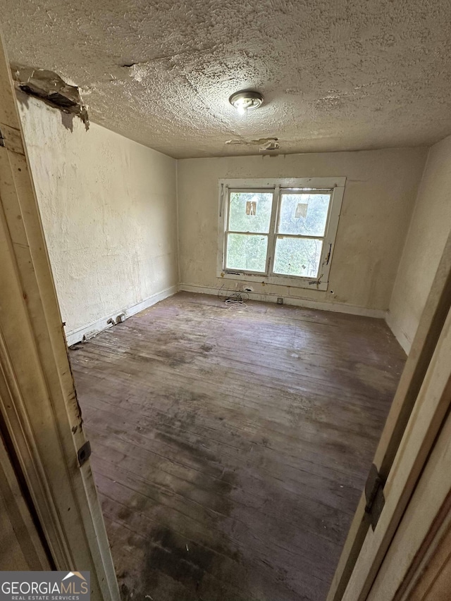 spare room with dark hardwood / wood-style flooring and a textured ceiling