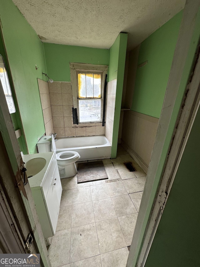 bathroom with vanity, a bathing tub, tile patterned floors, toilet, and a textured ceiling