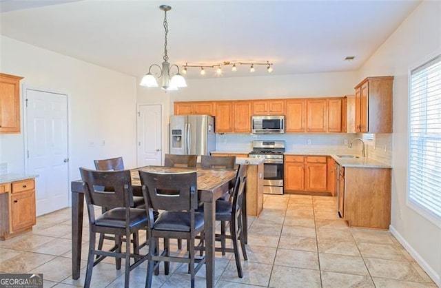 kitchen with hanging light fixtures, sink, decorative backsplash, appliances with stainless steel finishes, and a notable chandelier