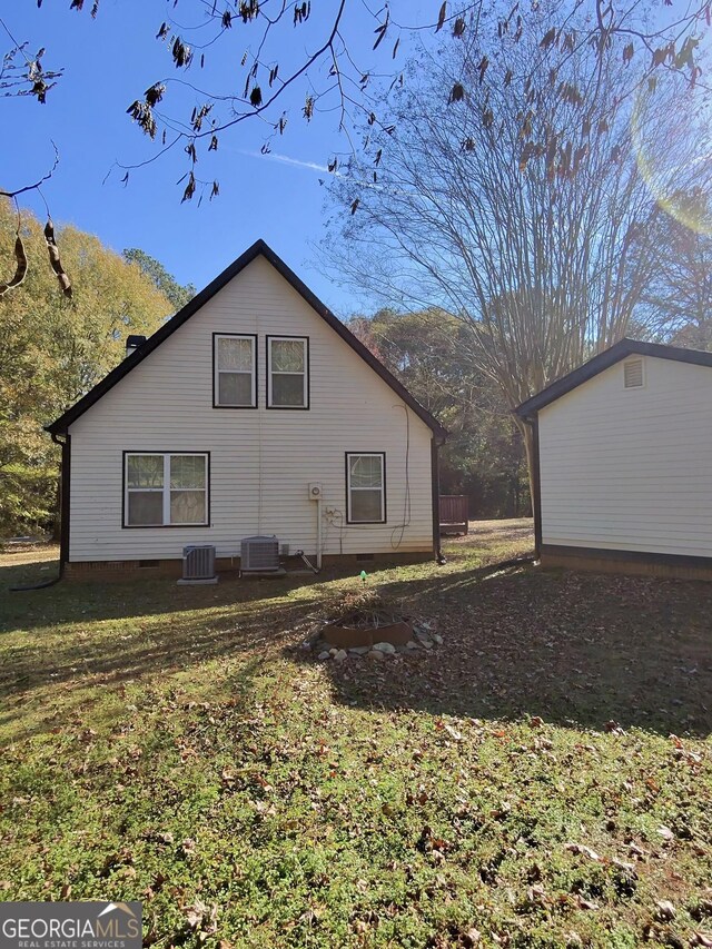 back of property with central AC unit and a lawn