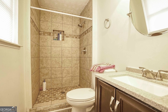 bathroom featuring tiled shower, vanity, and toilet