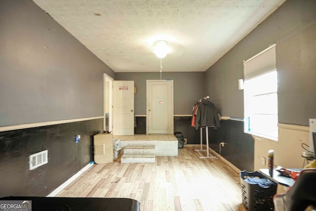 miscellaneous room featuring light wood-type flooring and a textured ceiling