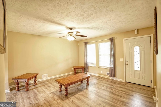 interior space with ceiling fan, light wood-type flooring, and a textured ceiling