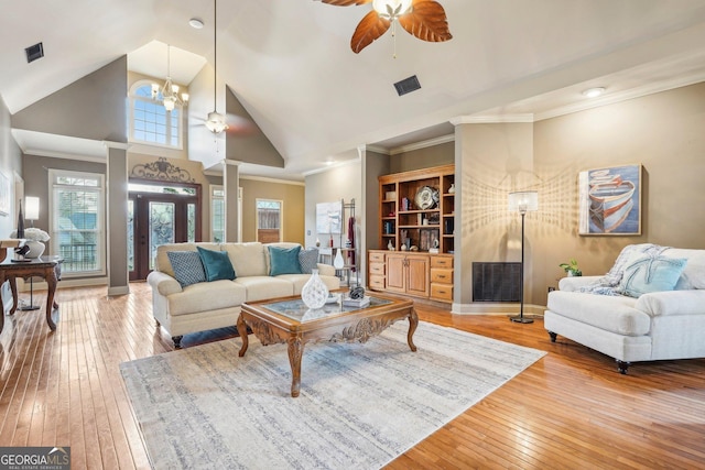 living room featuring built in shelves, high vaulted ceiling, hardwood / wood-style floors, ceiling fan with notable chandelier, and ornamental molding