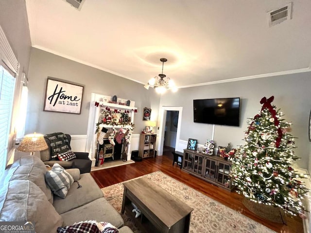 living room with hardwood / wood-style flooring, ornamental molding, and a chandelier