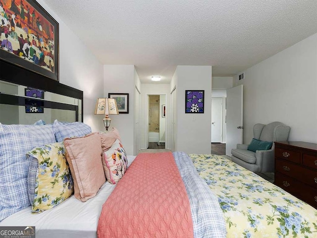 bedroom featuring a textured ceiling and ensuite bath