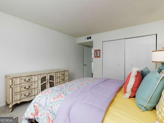 carpeted bedroom with a textured ceiling and a closet