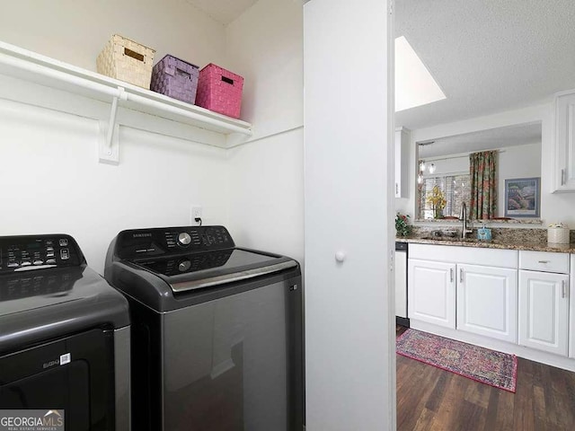 clothes washing area with dark wood-type flooring, washer and dryer, a textured ceiling, and sink