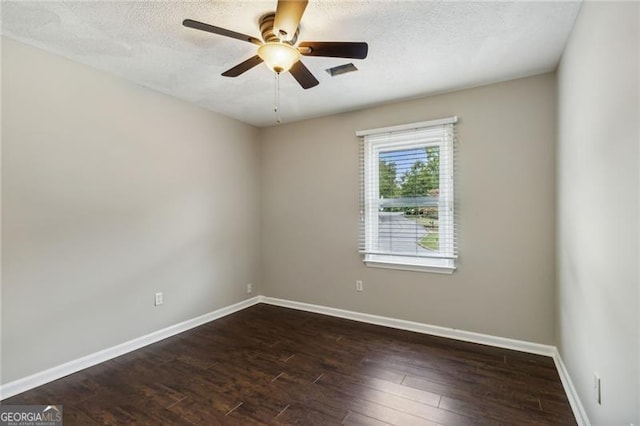 empty room featuring ceiling fan, dark wood-type flooring, and a textured ceiling