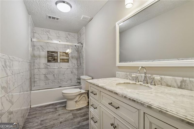 full bathroom with combined bath / shower with glass door, a textured ceiling, toilet, vanity, and hardwood / wood-style flooring