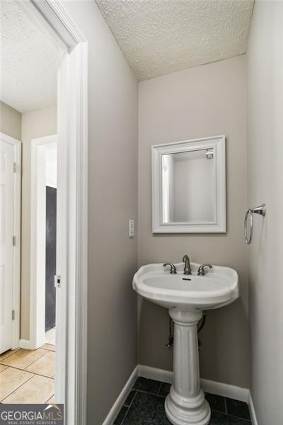 bathroom with tile patterned flooring and a textured ceiling