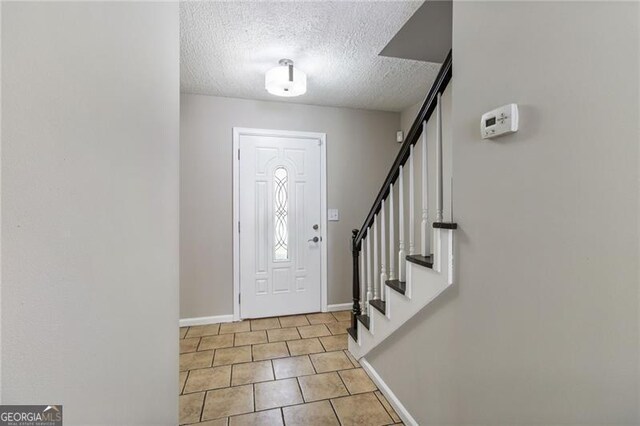 tiled entrance foyer featuring a textured ceiling