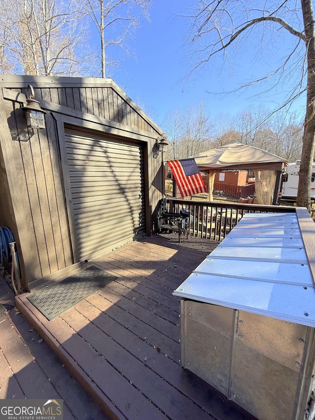 wooden terrace featuring a garage and an outbuilding