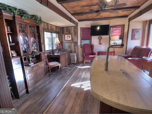 dining area with beamed ceiling, radiator heating unit, dark hardwood / wood-style flooring, and wood walls