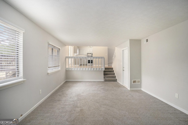 unfurnished living room featuring carpet flooring and a textured ceiling