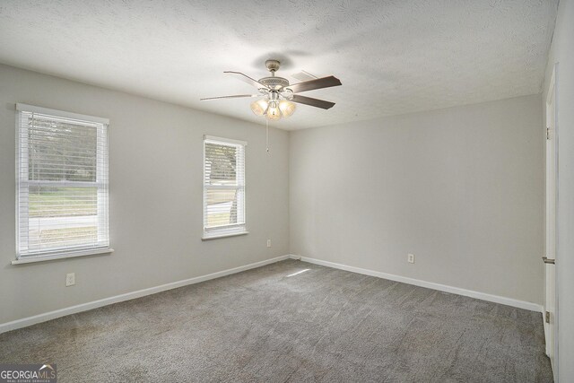 carpeted spare room with ceiling fan, a healthy amount of sunlight, and a textured ceiling