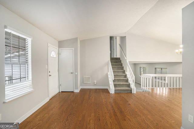 entryway with hardwood / wood-style flooring, a notable chandelier, and vaulted ceiling