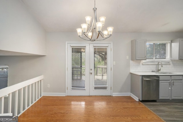 unfurnished dining area featuring wood-type flooring, french doors, a notable chandelier, and sink