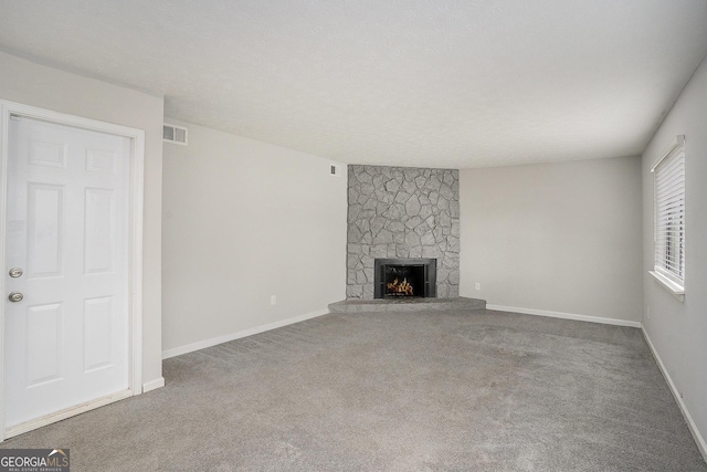 unfurnished living room with a stone fireplace and carpet floors