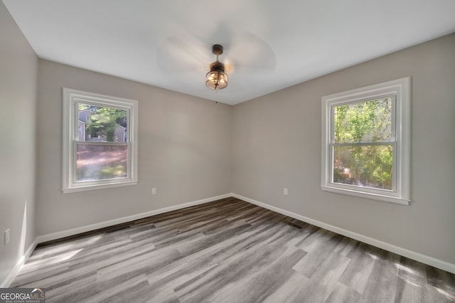 unfurnished room with a wealth of natural light, ceiling fan, and light wood-type flooring