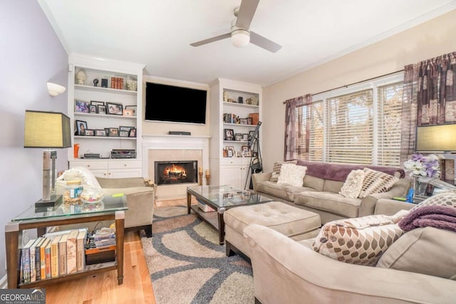 living room with light wood-type flooring, ceiling fan, and ornamental molding