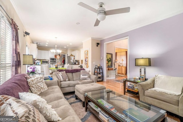 living room with light hardwood / wood-style floors, ceiling fan with notable chandelier, and ornamental molding