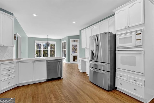 kitchen with white cabinets, decorative light fixtures, light wood-type flooring, and stainless steel appliances