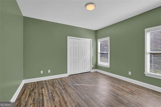 unfurnished bedroom featuring multiple windows, a closet, and wood-type flooring