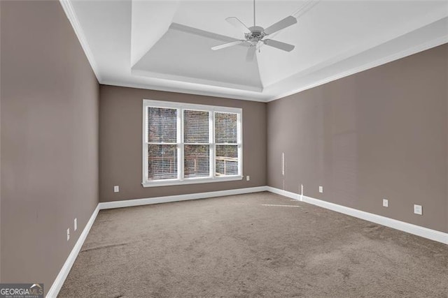 unfurnished room with a raised ceiling, ceiling fan, carpet, and ornamental molding