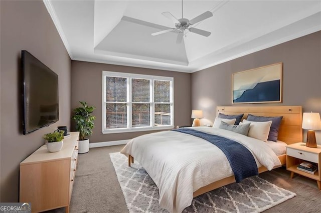 carpeted bedroom with ceiling fan, crown molding, and a tray ceiling