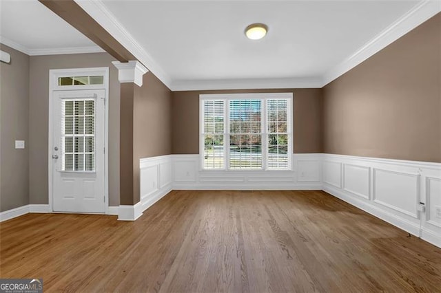 interior space featuring wood-type flooring, crown molding, and decorative columns