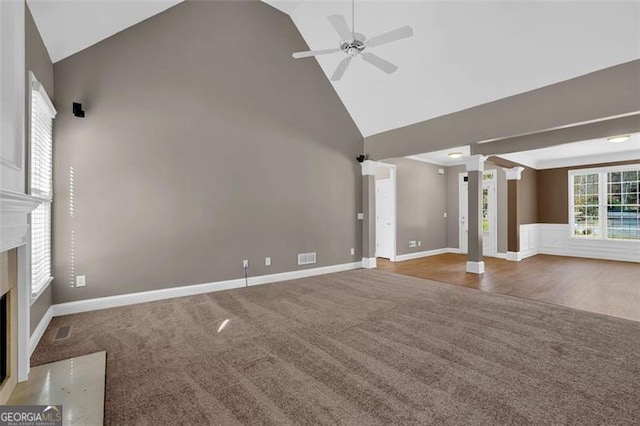 unfurnished living room with carpet floors, ornate columns, ceiling fan, and high vaulted ceiling