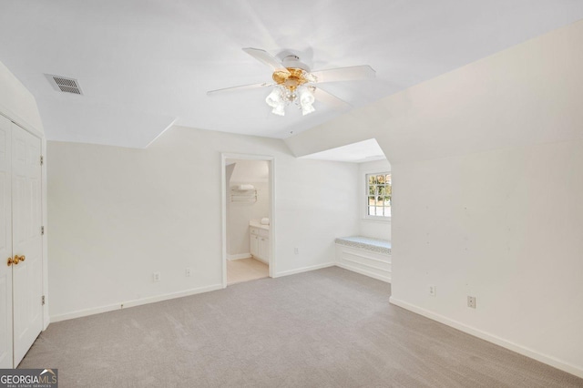 unfurnished bedroom with ceiling fan, light colored carpet, lofted ceiling, and connected bathroom