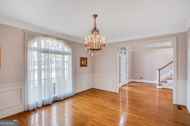 unfurnished dining area featuring a notable chandelier, light wood-type flooring, and ornamental molding