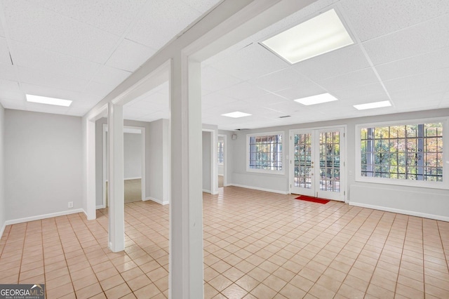 basement with a paneled ceiling and light tile patterned flooring