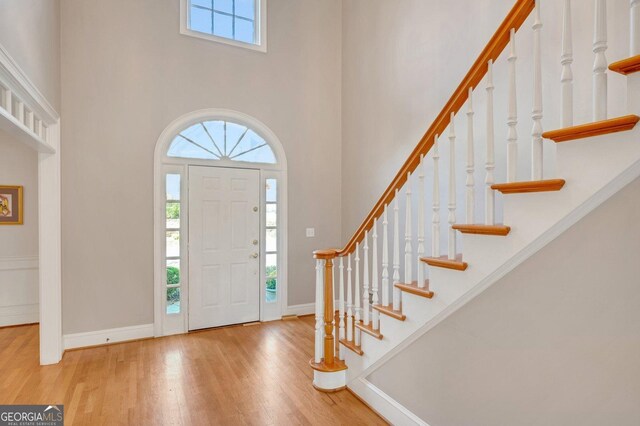 foyer entrance with light wood-type flooring and a towering ceiling