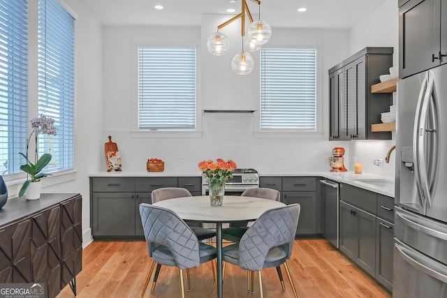 kitchen featuring plenty of natural light, light wood-type flooring, hanging light fixtures, and appliances with stainless steel finishes