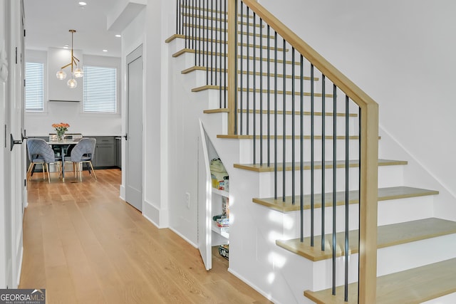 stairs with hardwood / wood-style floors and a notable chandelier