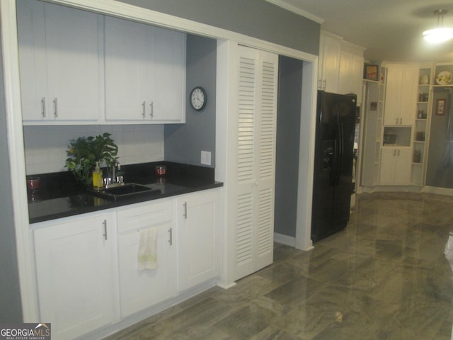 kitchen featuring white cabinets, black fridge with ice dispenser, backsplash, and sink