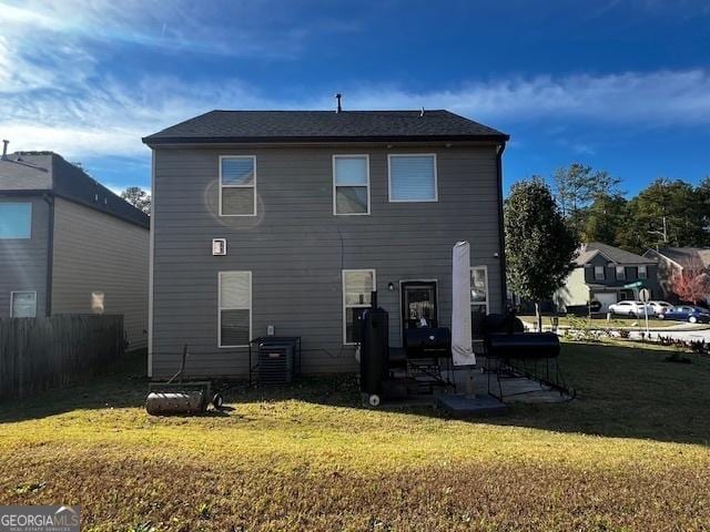 rear view of property featuring a yard and cooling unit