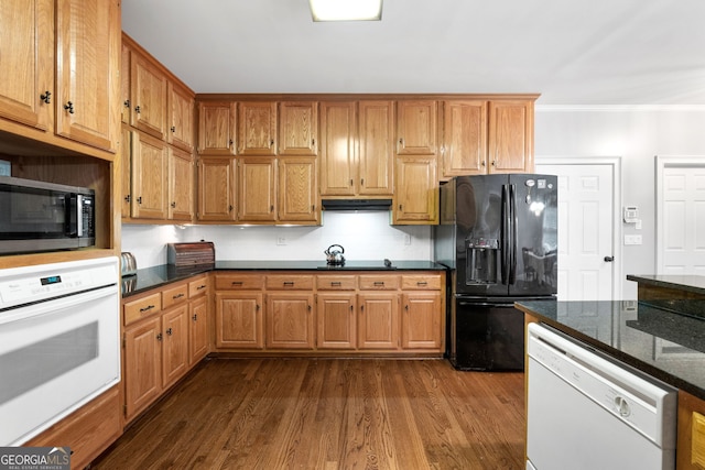 kitchen featuring white appliances, backsplash, dark wood-type flooring, crown molding, and dark stone countertops